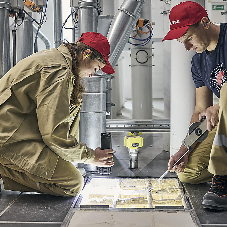 Eine Mitarbeiterin und eine Mitarbeiter von Rieper bei der Arbeit im Futtermittelwerk.